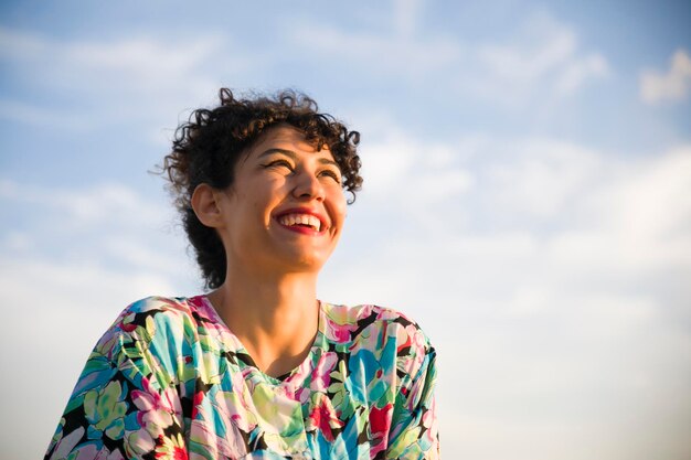 Vue à angle bas d'une femme joyeuse contre un ciel nuageux.