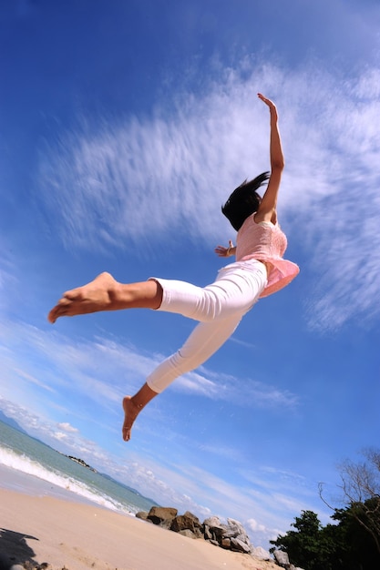 Vue à angle bas d'une femme sautant contre la mer à la plage