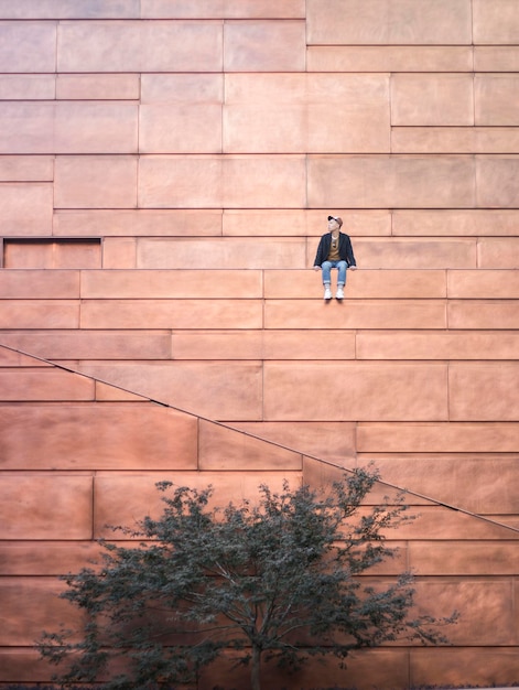 Vue d'angle bas de l'homme assis sur le bâtiment