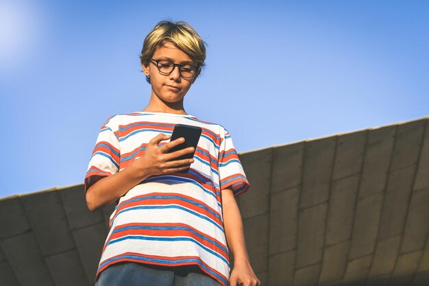 Vue d'angle bas d'un homme utilisant un téléphone intelligent contre un ciel clair