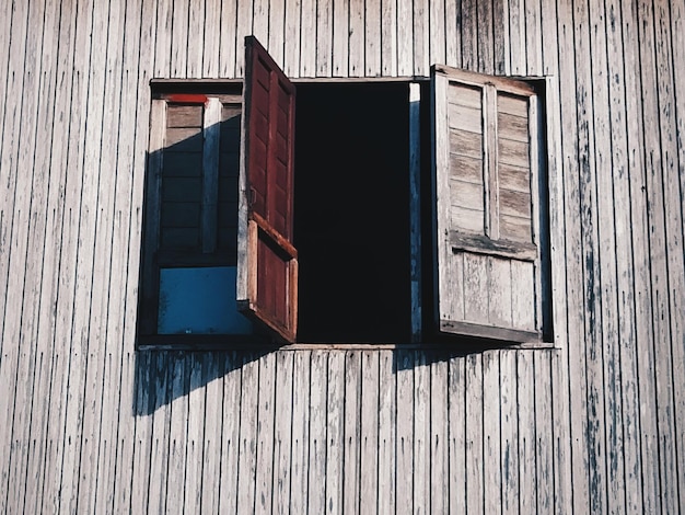 Photo vue d'angle bas d'une maison en bois avec une fenêtre ouverte pendant la journée ensoleillée