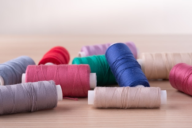 Vue d'angle de bobines de fil de coton colorés dispersés sur table en bois