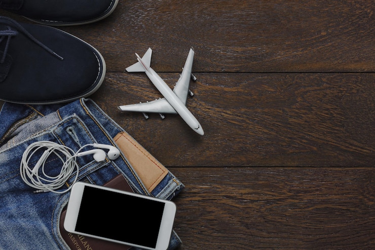 Photo vue d'angle élevé d'un avion jouet avec un téléphone portable et des écouteurs sur un jean avec des chaussures sur une table en bois