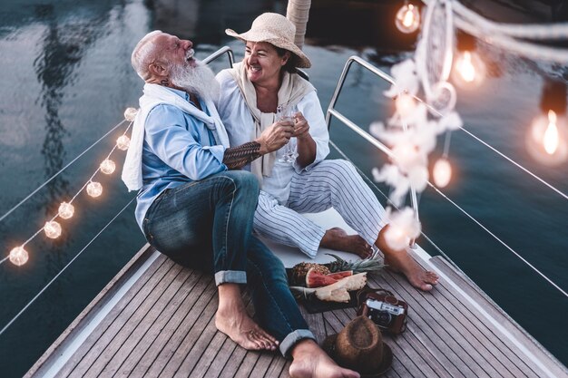 Photo vue d'angle élevé d'un couple joyeux assis sur un bateau au coucher du soleil