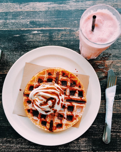Vue d'angle élevé de crème glacée fraîche sur waffle avec sauce au chocolat servie dans une assiette par smoothie