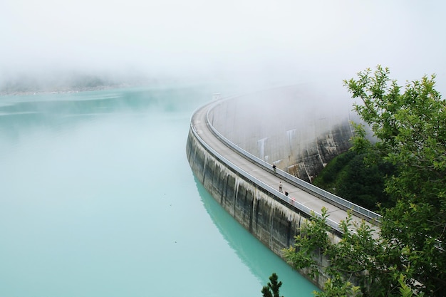 Vue d'angle élevé du barrage par la rivière par temps brumeux