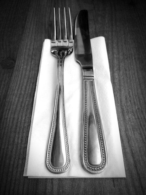 Photo vue d'angle élevé du couteau de table par fourchette sur une serviette à table