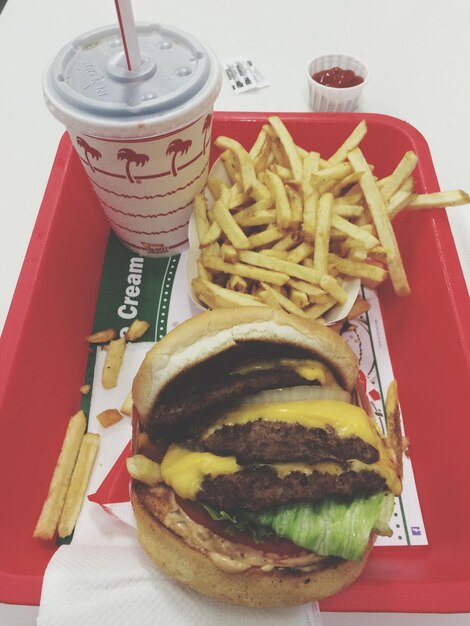 Photo vue d'angle élevé du hamburger et des frites avec boisson dans le récipient sur la table