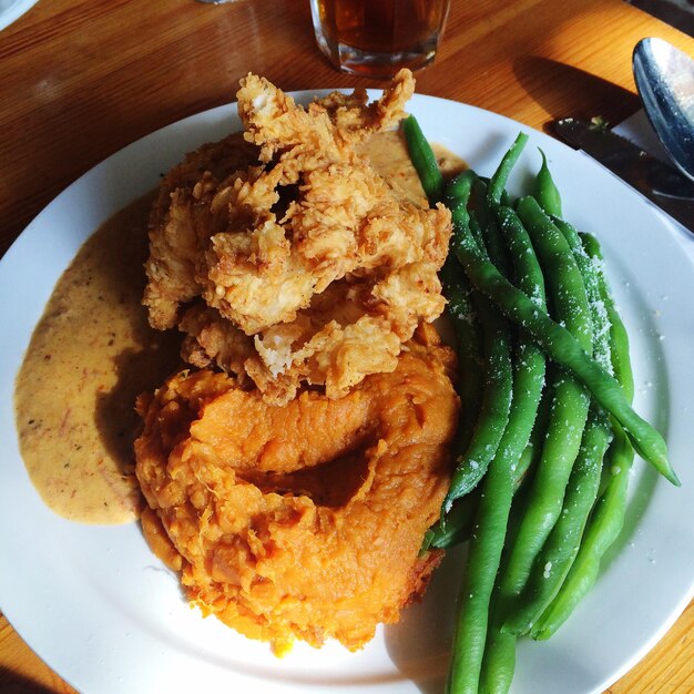 Photo vue d'angle élevé du poulet frit avec des haricots verts servis dans une assiette sur la table