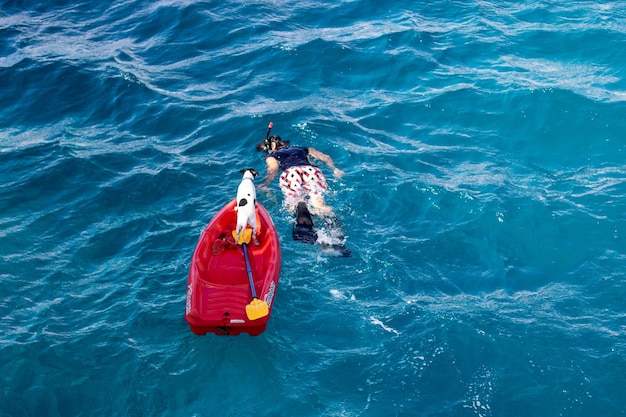 Photo vue d'angle élevé d'une femme nageant avec un chien dans un bateau en mer