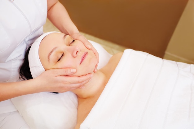 Vue d'angle élevé d'une femme recevant un massage facial dans un spa