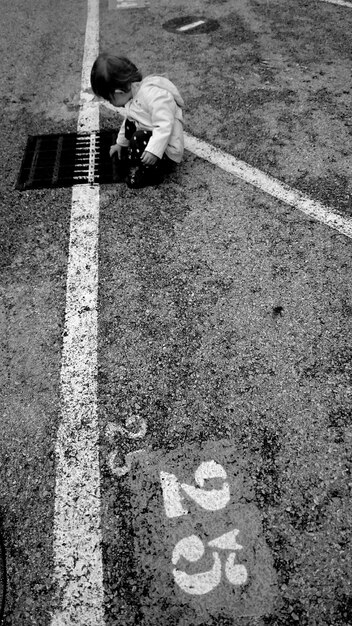 Photo vue d'angle élevé d'une fille accroupi sur la route