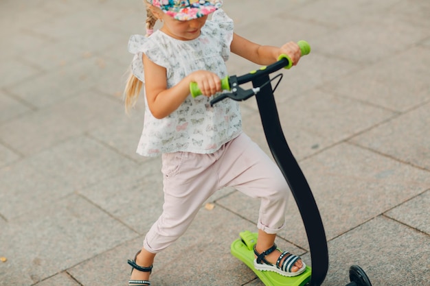 Vue d'angle élevé d'une fille sur un scooter de poussée sur un sentier piétonnier