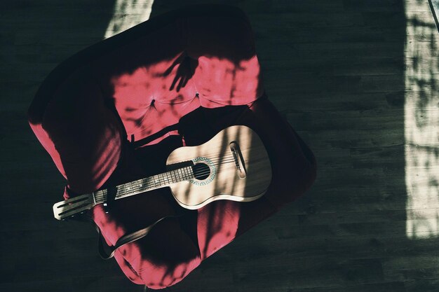 Photo vue d'angle élevé de la guitare sur la chaise sur le sol en bois dur à la maison.