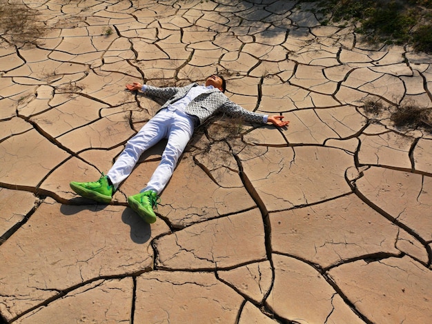 Photo vue d'angle élevé d'un homme avec les bras tendus allongé sur la terre sèche