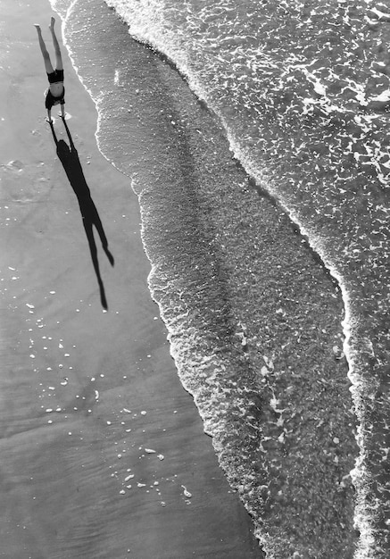 Photo vue d'angle élevé d'un homme faisant un handstand sur la plage