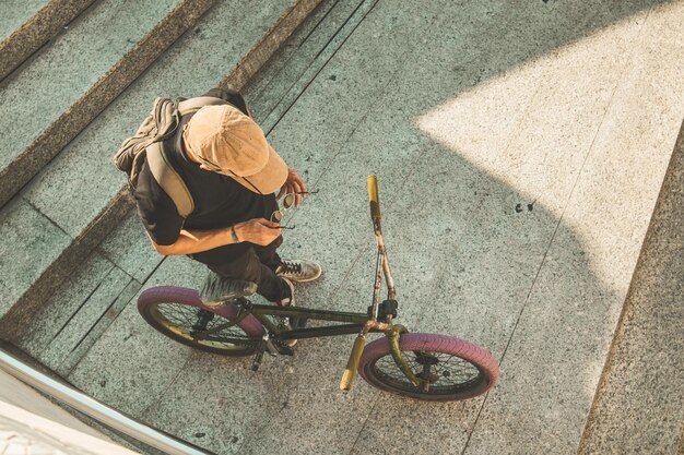 Photo vue d'angle élevé d'un homme avec un vélo sur l'escalier