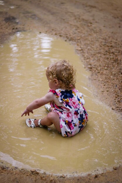 Photo vue d'angle élevé d'une jolie fille assise dans une flaque d'eau