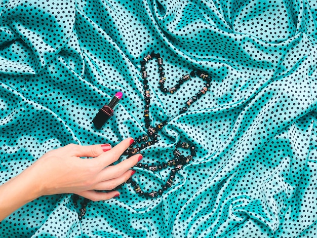 Photo vue d'angle élevé de la main de la femme par collier et rouge à lèvres sur le textile