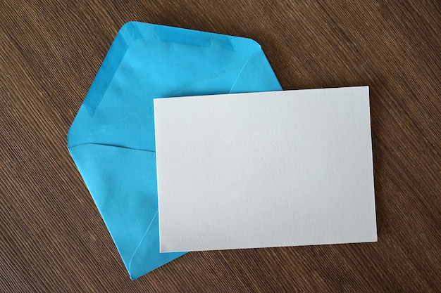 Photo vue d'angle élevé d'un papier blanc avec une enveloppe bleue sur une table en bois