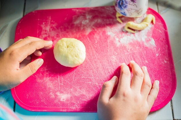 Photo vue d'angle élevé de la pâte à mâcher à la main sur la planche à couper à la table