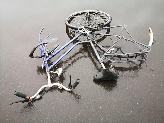 Photo vue d'angle élevé d'un vélo cassé sur une route mouillée