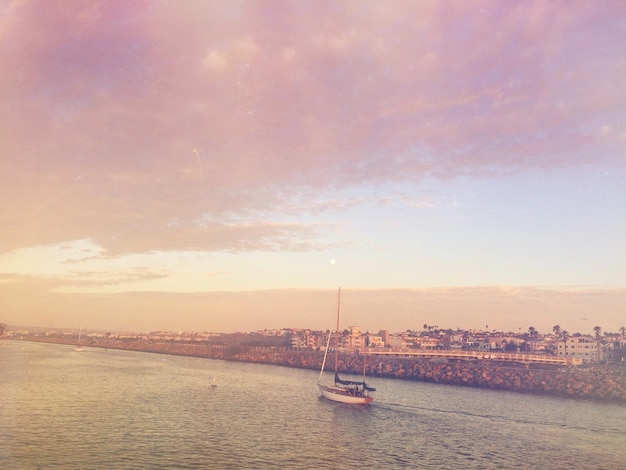 Vue d'angle élevé d'un voilier naviguant sur la mer par ville contre le ciel