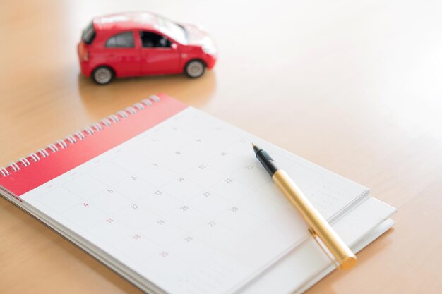 Photo vue d'angle élevé d'une voiture de jouet avec un stylo et un calendrier sur la table