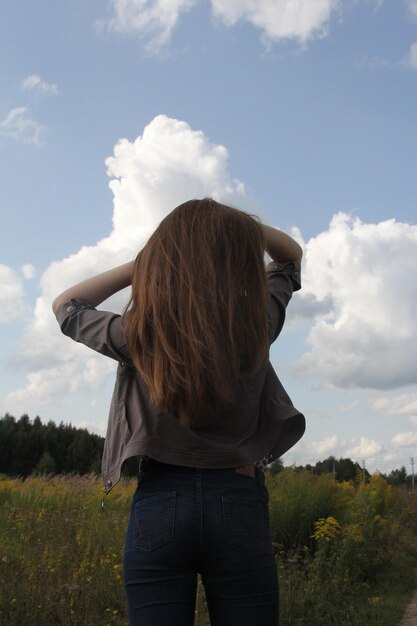 Vue arrière d'une adolescente debout sur le terrain contre le ciel
