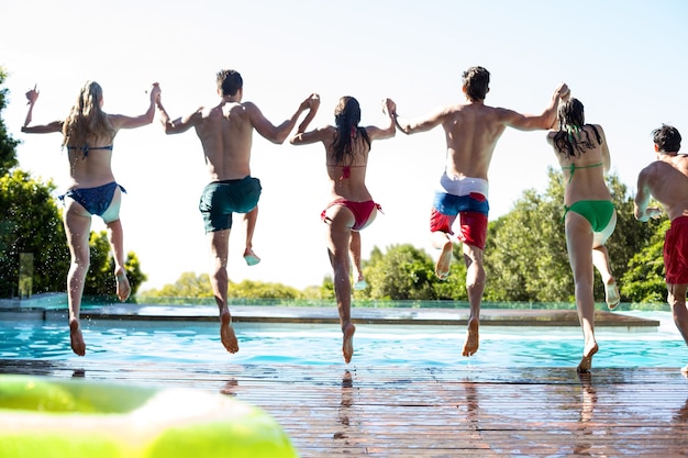 Vue arrière d'amis sautant dans la piscine