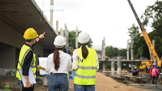 Vue arrière des architectes et du superviseur exécutif discutant des détails du projet sur le chantier de construction Concept de construction de l'ingénieur de l'industrie