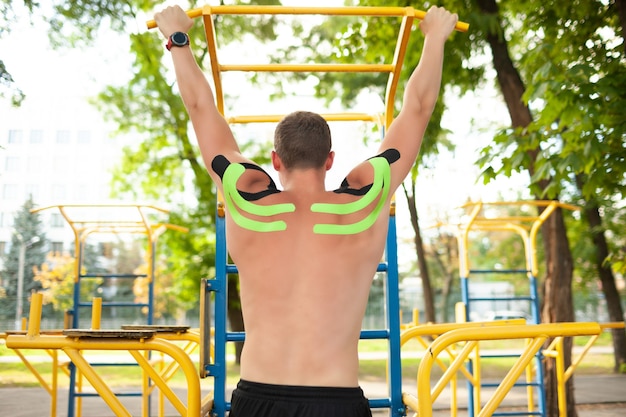 Vue arrière de l'athlète masculin professionnel avec bande kinésiologique colorée sur le dos