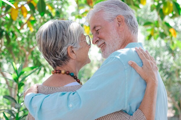 Vue arrière d'un beau couple de personnes âgées aux cheveux blancs embrassant tout en marchant dans les bois Grands-parents âgés souriants profitant d'une retraite sereine