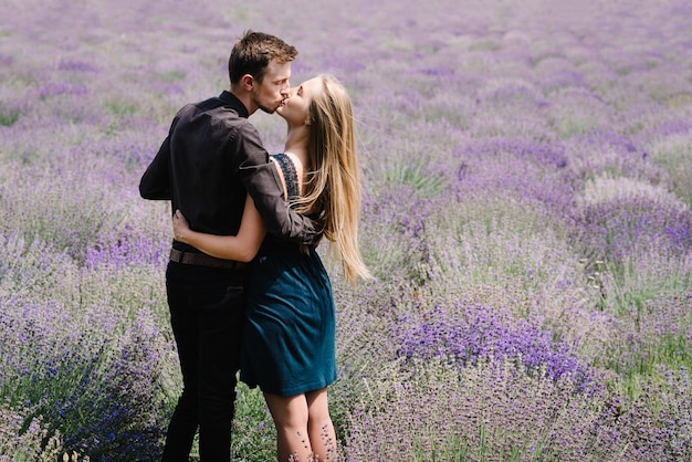 Vue arrière charmant jeune couple amoureux dans un champ de lavande pourpre s'embrasser et passer un moment romantique Homme et femme dans les champs de fleurs Voyage de lune de miel Jeune marié Voyage de couple heureux Prés de lavande