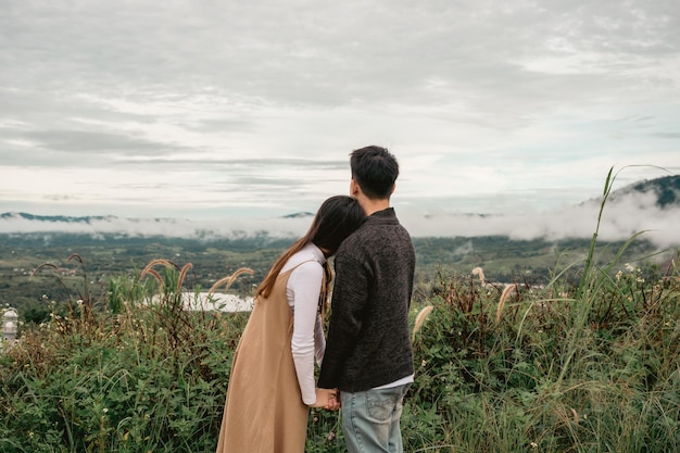 Vue arrière d'un couple asiatique se tenant la main et se tenant la main en regardant la nature dans la campagne en vacances