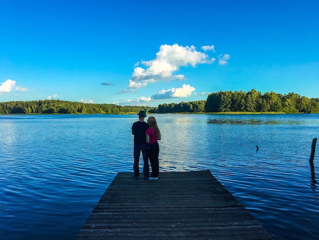Photo vue arrière d'un couple debout sur la jetée contre le lac