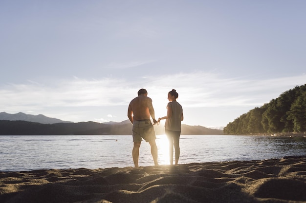 Vue arrière d'un couple debout sur le rivage à la plage contre le ciel