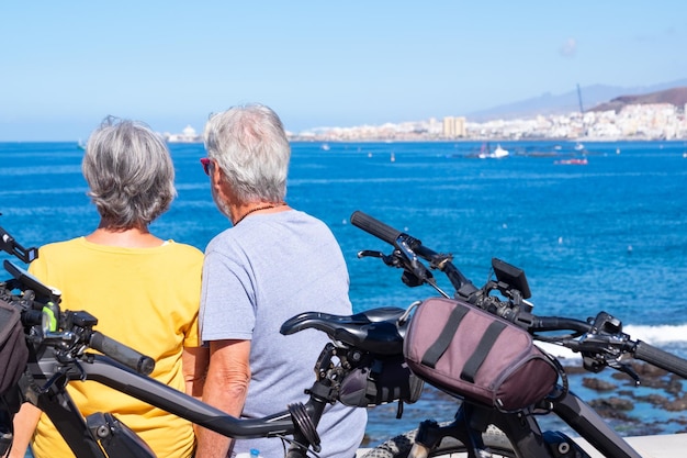 Vue arrière d'un couple de personnes âgées assis sur la falaise lors d'une excursion en mer profitant d'un mode de vie sain