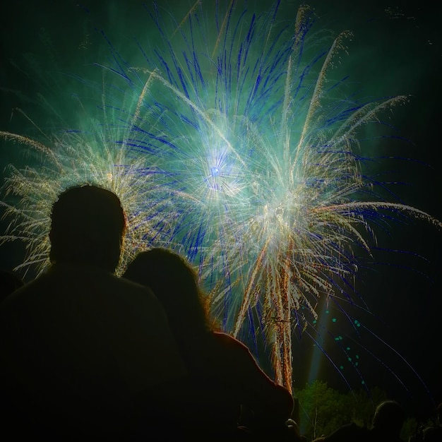 Photo vue arrière d'un couple regardant un feu d'artifice explosant dans le ciel
