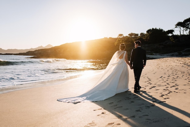 Vue arrière d'un couple se promenant sur la plage au coucher du soleil