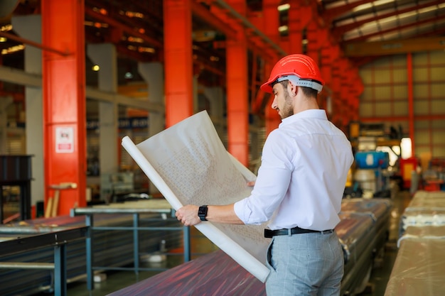 Vue arrière derrière l'arrière Portrait de l'architecte et du constructeur de génie civil tenant un plan d'aménagement sur l'usine en chantier