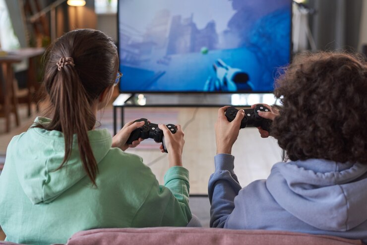 Photo vue arrière de deux amis jouant au jeu vidéo en équipe assis sur un canapé devant une grande télévision