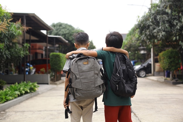 Vue arrière de deux étudiants s'embrassent pour aller à l'école