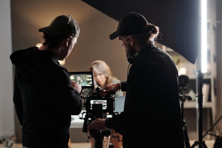 Photo vue arrière de deux jeunes hommes debout devant la caméra et utilisant le steadicam