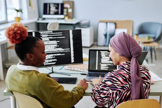 Photo vue arrière de deux programmeuses écrivant du code ensemble