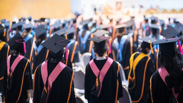 Vue arrière des diplômés universitaires alignés pour l'obtention d'un diplôme lors de la cérémonie de remise des diplômes universitaires. Les diplômés universitaires se rassemblent lors de la cérémonie de remise des diplômes universitaires. Foule des diplômés.