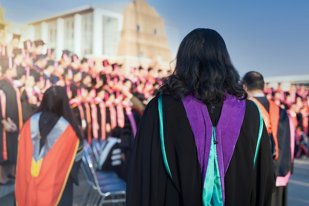 Vue arrière des diplômés universitaires alignés pour l'obtention d'un diplôme lors de la cérémonie de remise des diplômes universitaires. Les diplômés universitaires se rassemblent lors de la cérémonie de remise des diplômes universitaires. Foule des diplômés.