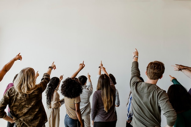 Vue arrière de diverses personnes pointant vers un mur blanc vierge