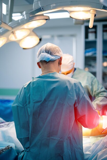 Photo vue arrière du chirurgien masculin portant un bonnet de protection et un masque debout et préparant l'opération medic pendant l'opération concept de médecine