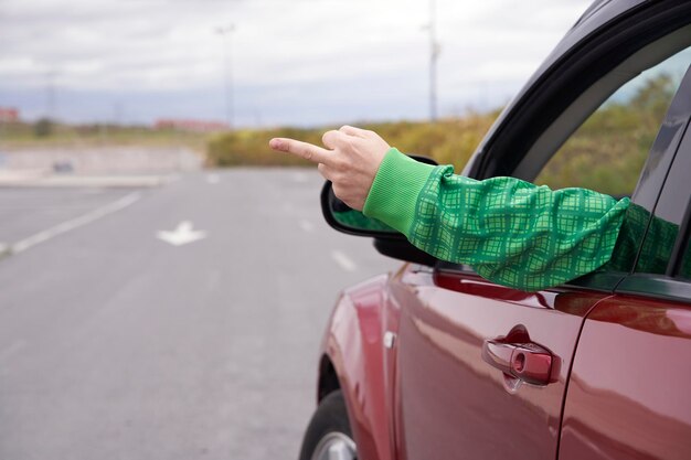 Vue arrière du conducteur montre le majeur jeter les fenêtres va te faire foutre avec un signe Concept de rage au volant